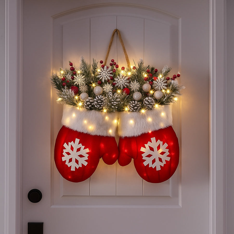 Red mitten Christmas wreath with lights, pine, red berries and snowflakes hanging on a white front door